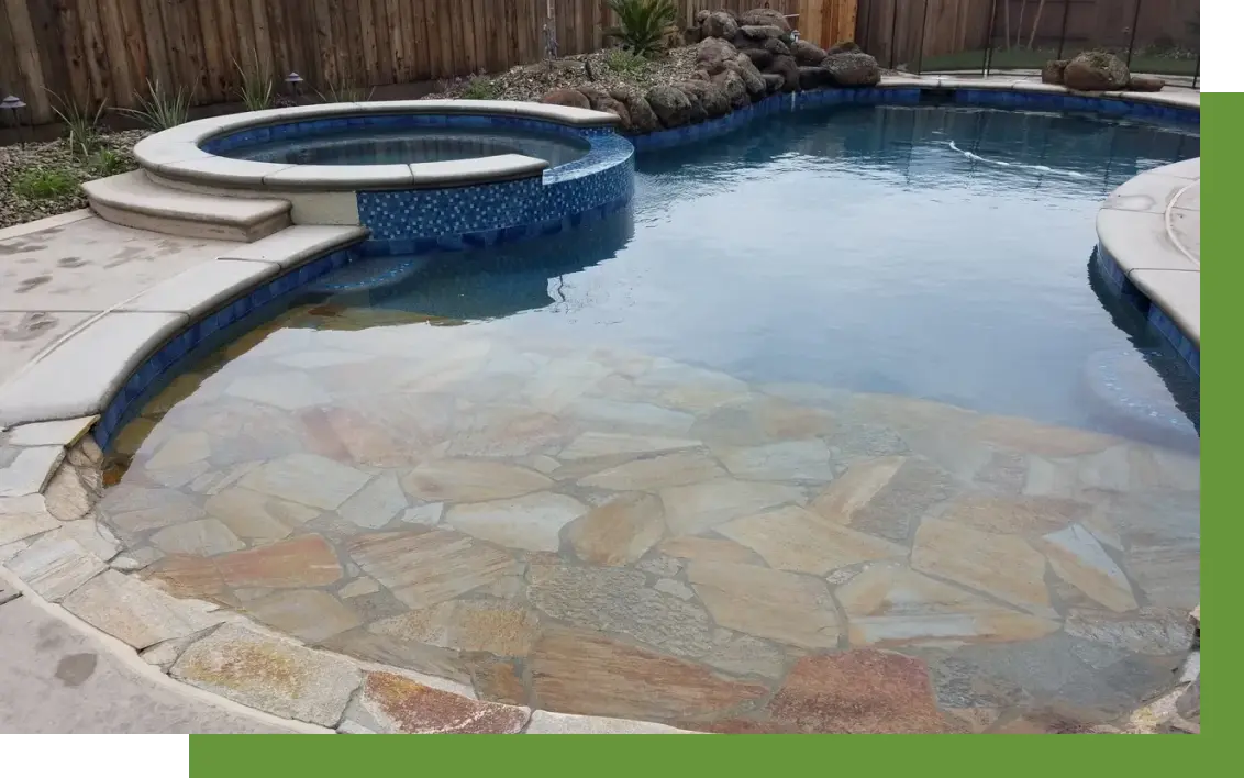 A pool with a stone wall and a rock garden.