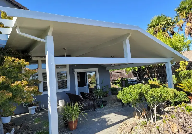 A patio with a white roof and two chairs.