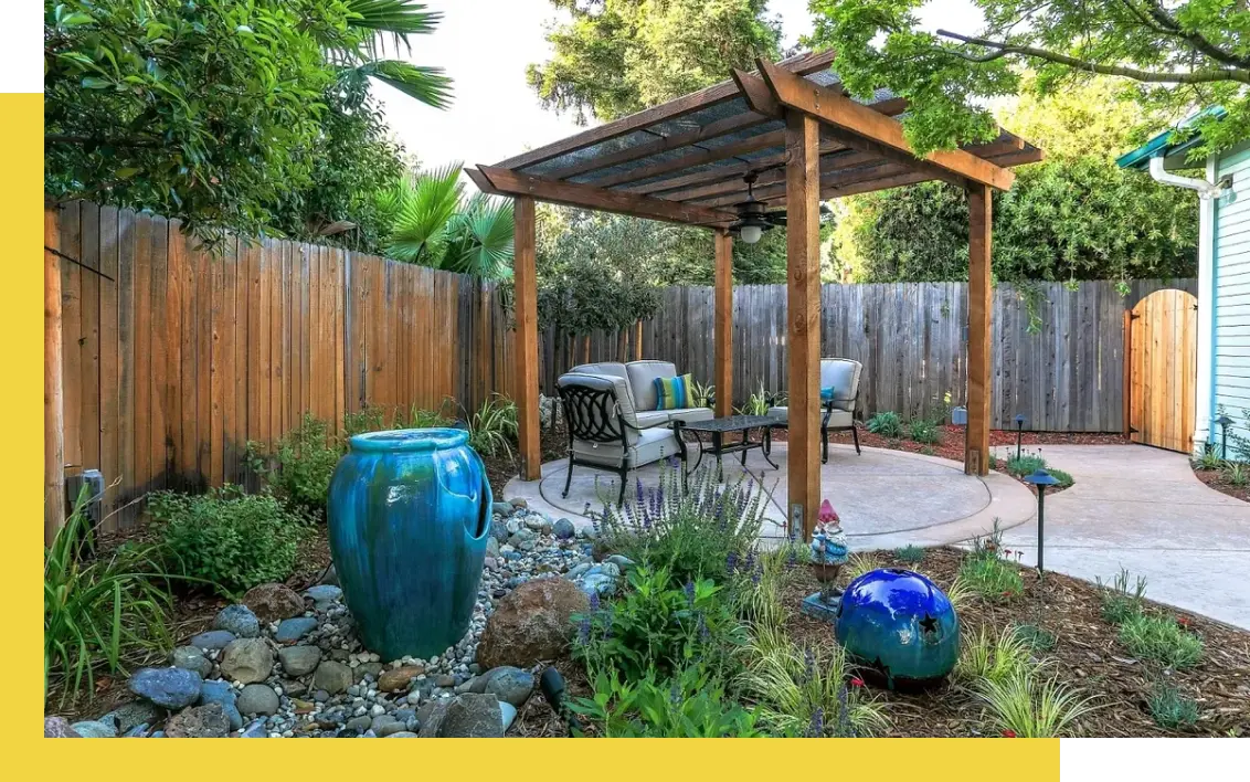 A backyard with a wooden pergola and blue glass vase.