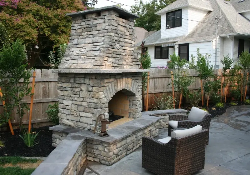 A patio with chairs and a fireplace in the middle of it.